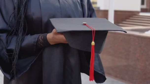 Магістри капелюха з червоною китицею на руці випускника університету. Крупним планом вид з відкритими сходами на задньому плані — стокове відео