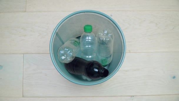 Ένα αντρικό χέρι παίρνει εναλλάξ πέντε πλαστικά μπουκάλια διαφορετικών χρωμάτων και όγκων από το σκουπιδοτενεκέ του γραφείου. Διαλογή απορριμμάτων. Ανακύκλωση πλαστικών — Αρχείο Βίντεο