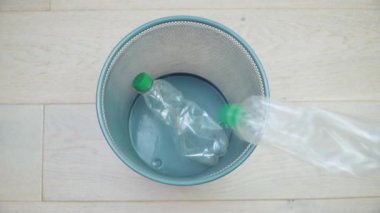Boş bir çöp tenekesinde birbirinin aynı beş plastik şişe var. Plastik atık tasnif ve işleme. Çöp ayıklama. Geri dönüşüm