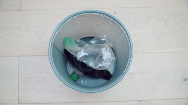 Un bote de basura vacío contiene cinco botellas de plástico dobladas y una botella de vidrio verde de cerveza. Basura mezclada. Clasificación y procesamiento de residuos de plástico y vidrio. Clasificación de basura. Reciclaje — Vídeo de stock