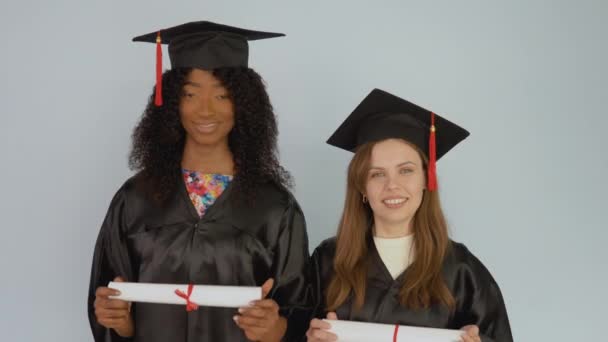 Jóvenes afroamericanos y caucásicos se colocan en la asignación y tienen diplomas horizontales — Vídeo de stock