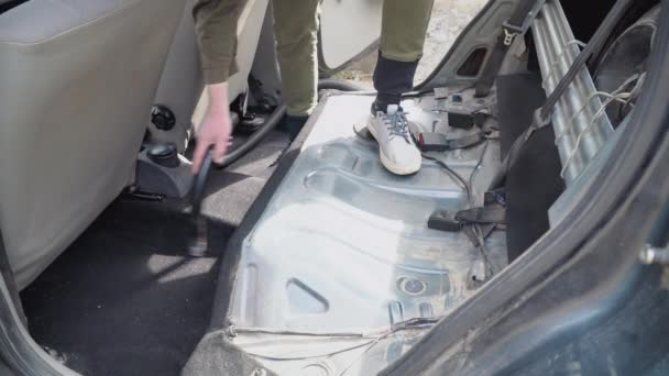 Detalle automático de un viejo coche usado. El interior se limpia con una aspiradora. Un hombre con ropa de trabajo limpia el coche del polvo y la suciedad. — Vídeos de Stock