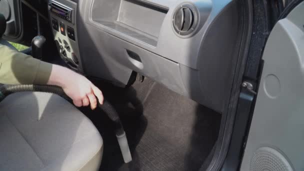 自动详细说明。一个带喷嘴的真空吸尘器用来清洗汽车前排座位附近的地板。一个穿着工作服的人把汽车前排的座位上的灰尘和泥土都擦干净了 — 图库视频影像