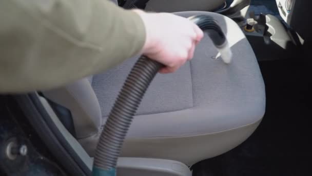 Detale samochodowe. Przednie siedzenia samochodu czyszczone są odkurzaczem z dyszą do czyszczenia studni. Mężczyzna w roboczym ubraniu czyści przednie siedzenia samochodu z kurzu i brudu. — Wideo stockowe