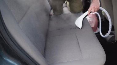 Eski bir arabanın otomatik temizliği. Arabanın içi bir buharlı gemiyle temizlenmiş. İş kıyafetli bir adam arabanın arka koltuklarını tozdan ve pislikten temizler..