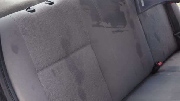 Dettaglio automatico di una vecchia auto usata. L'interno dell'auto viene pulito con un aspirapolvere con un detergente. Un uomo in abiti da lavoro pulisce i sedili anteriori della macchina da polvere e sporcizia. — Video Stock