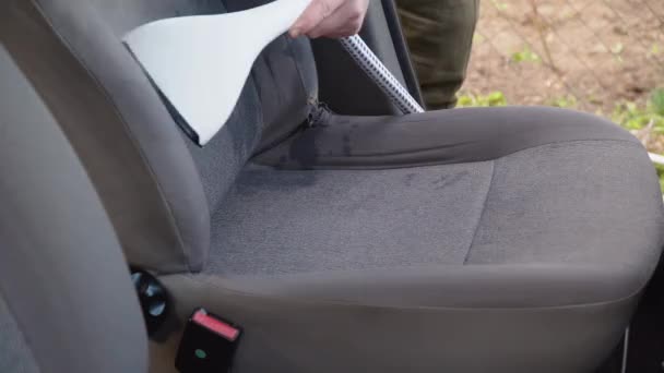 Automatyczne detalowanie starego używanego samochodu. Wnętrze samochodu czyszczone jest parownikiem. Mężczyzna w roboczym ubraniu czyści przednie siedzenia samochodu z kurzu i brudu.. — Wideo stockowe