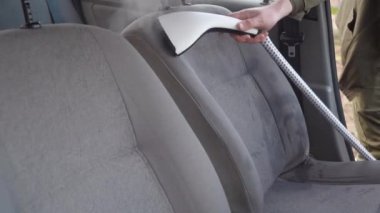Eski bir arabanın otomatik temizliği. Arabanın içi bir buharlı gemiyle temizlenmiş. İş elbiseli bir adam arabanın ön koltuklarını tozdan ve pislikten temizler..