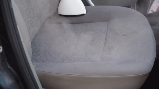 Dettaglio automatico di una vecchia auto usata. L'interno dell'auto viene pulito con un vapore. Un uomo in abiti da lavoro pulisce i sedili anteriori della macchina da polvere e sporcizia. — Video Stock