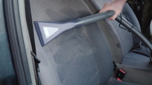Seorang pria membersihkan kursi depan mobil dari debu dan kotoran. Kursi depan mobil dibersihkan dengan nozzle untuk pembersih basah furnitur dengan agen pembersih. Detail otomatis — Stok Video