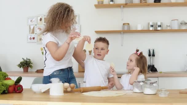 Οικογενειακή διασκέδαση με παιδιά. Δημιουργικότητα και μαγειρική για παιδιά. Μητρότητα. Οικογένεια ξανθών σε λευκά μπλουζάκια δείχνουν κύκλους με κομμένα φύλλα και κοιτάξτε την κάμερα. — Αρχείο Βίντεο