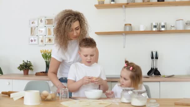 Annesiyle oğlu kasede yumurta kırıyor. Yaratıcılık ve çocuklar için yemek pişirme. Annelik. Beyaz tişörtlü ve kot pantolonlu sarışınların ailesi — Stok video