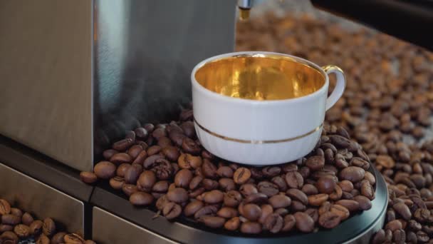 新鮮なコーヒーに食欲をそそる泡で満たされた金色の磁器のカップとヴィンテージホワイト。カップの下とその背景にあるコーヒー豆 — ストック動画