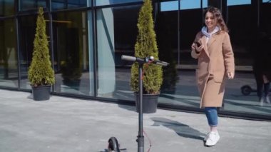 Genç bir kız cep telefonu uygulaması kullanarak elektrikli scooter kiralıyor. Turist telefonu başvurusu. Gençler ve iş adamları için modern aletler. Ekolojik Şehir Taşımacılığı