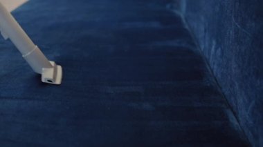 Temizliği kolaylaştıran teknolojiler. Modern ev aletleri. Kadın ev hanımı döşeme mobilyalarının temizlenmesi için özel bir hortumla kanepeyi süpürüyor.