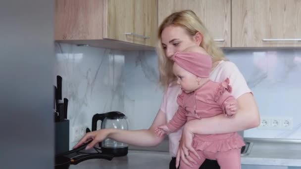 Anya ételt készít a karjaiban tartva a babát. Mindennapi anyák. Anyák leckéje — Stock videók