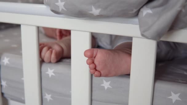 Il braccio e la gamba dei bambini addormentati sono visibili da sotto la coperta nella culla — Video Stock