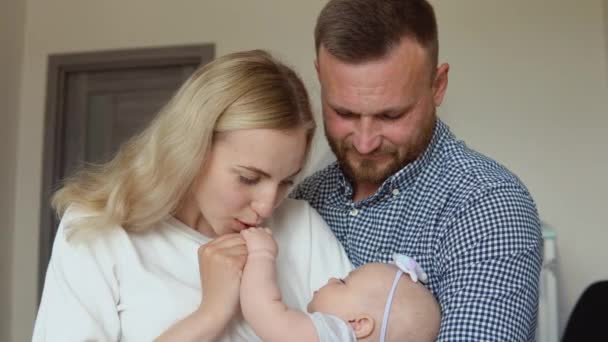 Madre e padre abbracciano e ammirano il loro bambino mentre dorme tra le braccia della madre. Paternità e maternità. Famiglia tradizionale — Video Stock