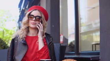 Kruvasanla kahve molası. Rahat bir sokakta cep telefonuyla konuşan modern şehirli genç kadın.