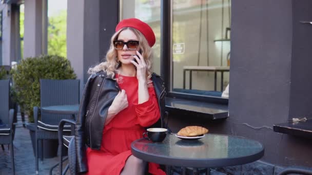 Kaffeepause mit Croissant. Moderne urbane junge Frau telefoniert auf Restaurantterrasse — Stockvideo