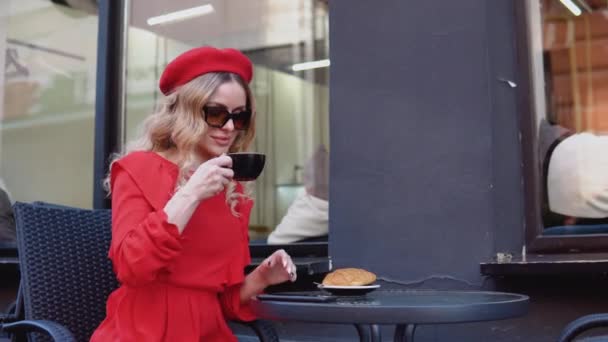 Estética de colores rojo y negro. Desayuno francés. Mujer romántica joven bebiendo café con un croissant — Vídeos de Stock