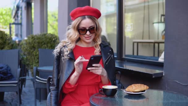 Pausa para café com croissant. Jovem urbana moderna trabalhando online no telefone celular no terraço do restaurante. Acesso ininterrupto à Internet — Vídeo de Stock