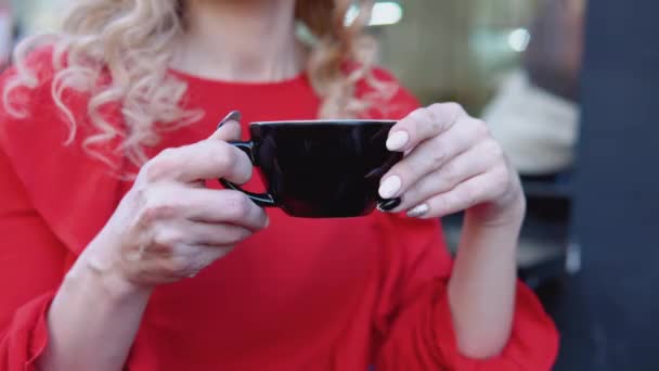 Black cup of coffee in female hands on a red background. Outdoor shooting on the street — Stock Video