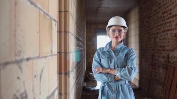 Una arquitecta o albañil se encuentra en una casa de nueva construcción con paredes sin tratar. El proceso de construcción de viviendas para la familia. Materiales de construcción — Vídeos de Stock