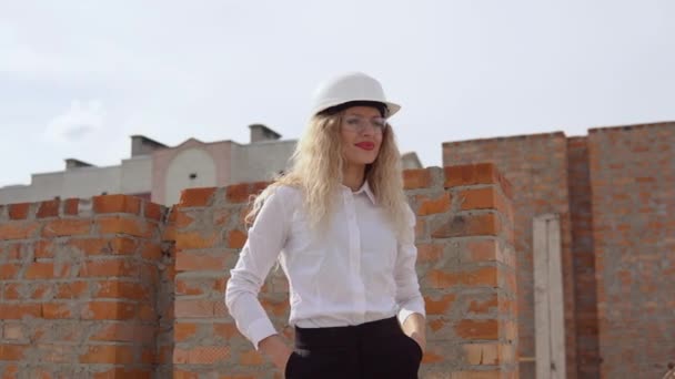 사업 복을 입은 한 여성 건축가 가 공사장의 야외 공중에서 1 층에 서 있다. 건축가가 물체를 조사하다 — 비디오