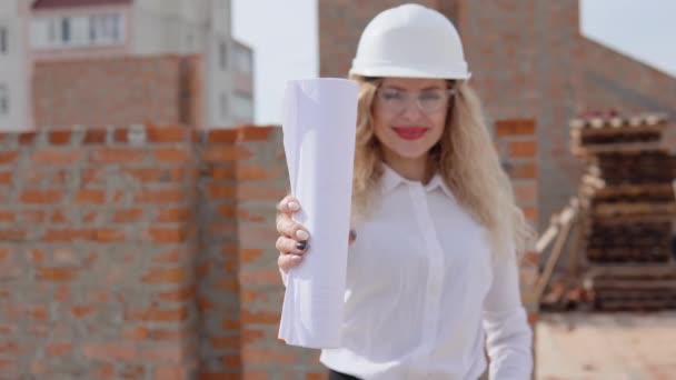 Женщина-архитектор в деловой одежде, стоящая на улице на стройке с планом строительства — стоковое видео