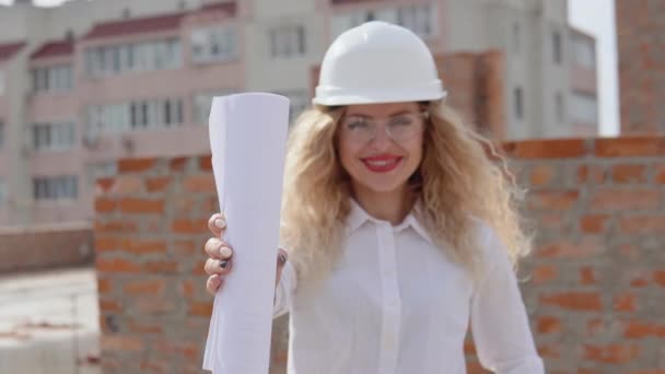 İnşaat planıyla birlikte inşaat alanının dışında duran iş elbiseli kadın mimar. — Stok video