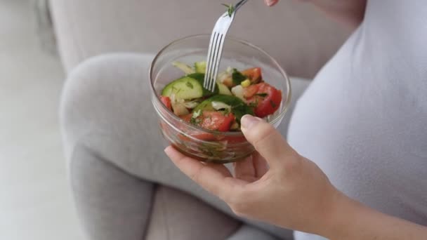 Elinde taze sebze salatası ve çatal tutan ev elbiseli hamile bir kadın. Hamileliğin üçüncü üç ayı. Hamile bir kadının sağlığıyla ilgilen. — Stok video