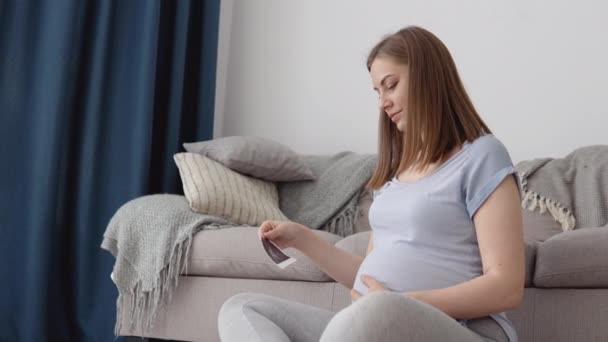 Kobieta w ciąży patrzy na pierwsze zdjęcie płodu nienarodzonego dziecka. Nowoczesne technologie monitorowania ciąży. Określanie płci dziecka za pomocą ultradźwięków — Wideo stockowe