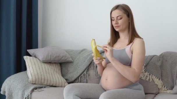 Dieta equilibrada e monitoramento de peso de uma mulher grávida. Cálcio como um elemento traço necessário para o desenvolvimento fetal. Mulher grávida come banana e frutas — Vídeo de Stock