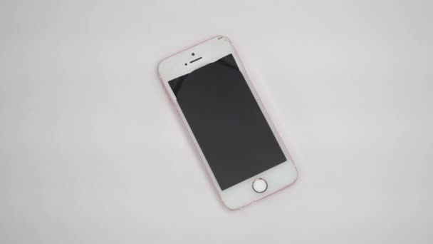 New York, USA - 1 LUGLIO 2021: Un iPhone rosa e bianco giace sul fondo di una vasca bianca piena d'acqua. Il telefono cellulare è coperto d'acqua — Video Stock