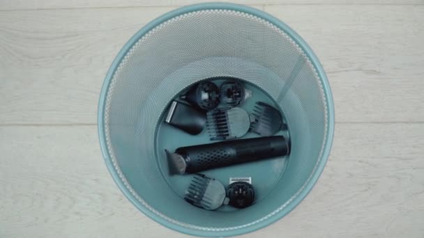 Service in a hairdresser, barbershop, beauty salon. A faulty hair clipper with attachments lies at the bottom of the trash — Stock Video