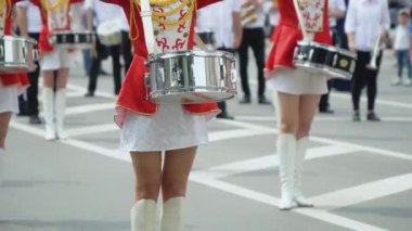 Sokak performansı, davulcu kızların şehir caddesinde kırmızı kostümlü yürüyüşleri. Geçit töreninde kırmızı üniformalı genç kız davulcu