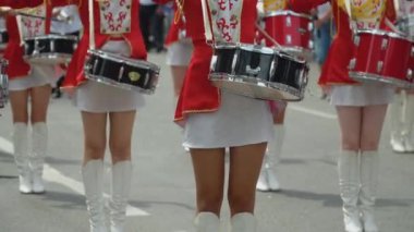 Sokak performansı. Kadın davulcuların yakın plan fotoğrafları. Geçit töreninde kırmızı üniformalı adamlar.