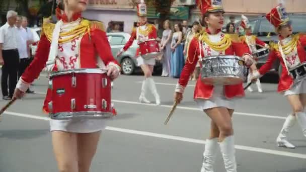 Ternopil, Ukrayna 2 Temmuz 2021: Şehir caddesinde kırmızı kostümlü baterist kızların sokak performansı. Geçit töreninde kırmızı üniformalı genç kız davulcu — Stok video