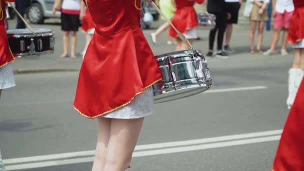 Вуличне виконання святкового маршу дівчаток барабанщиків у червоних костюмах на міській вулиці. Молоді дівчата барабанщик у червоній старовинній формі на параді — стокове відео