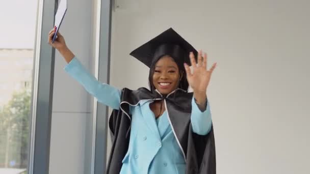 Uma afro-americana graduada em um terno mestrado clássico e dança mantle com um diploma em suas mãos e sorri. Licenciatura em Medicina. Ensino superior para mulheres — Vídeo de Stock