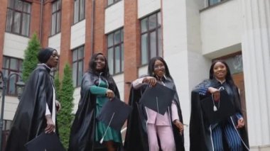 Afrika kökenli bir üniversiteden ya da üniversiteden kare cübbeli mutlu mezunlar ustanın kare şapkalarını yukarı fırlatırlar. Öğrenci değişim programı. Avrupa 'da kadınlar için yüksek öğrenim