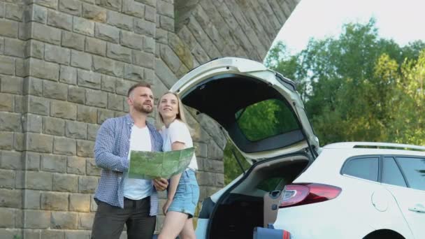 A boldog pár autóval utazik. Férfiak és nők nézik az útitervet. Aktív pihenés a család számára — Stock videók