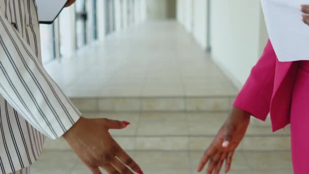 Dos damas de negocios afroamericanas glamorosas con un traje de rayas blancas y un traje rosa se dan la mano. Vista de cerca de las manos — Vídeos de Stock