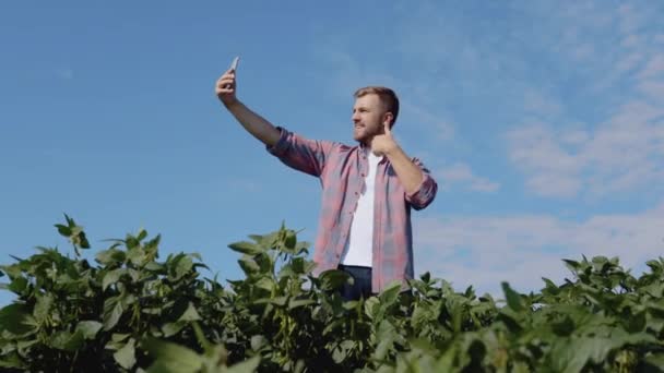 En ung bonde tar en selfie på fältet sojabönor han odlar — Stockvideo