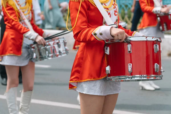 Sokak performansı, davulcu kızların şehir caddesinde kırmızı kostümlü yürüyüşleri. Geçit töreninde kırmızı üniformalı genç kız davulcu