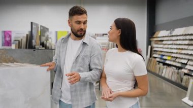 Genç ve mutlu bir çift, banyo veya mutfak tadilatı için yeni seramik veya porselen fayanslar seçerek, büyük bir hırdavatçıda iç dizayn malzemeleri hakkında ortak bir karar veriyorlar.
