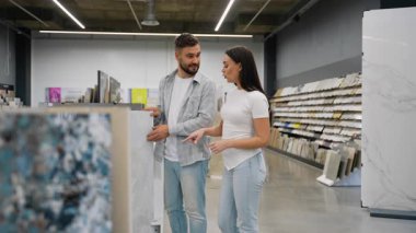 Mutlu çift ev yenileme projeleri için yeni seramik fayanslar seçiyor ve geniş bir modern hırdavatçı galerisindeki yapı malzemeleri çeşitliliğine göz atıyor.