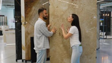 Mutlu çift, bir hırdavatçıda yeni seramik fayanslar seçiyor. Heyecanlı genç aile banyo veya mutfak yenileme projesi için tasarım ve malzeme seçeneklerini tartışıyor