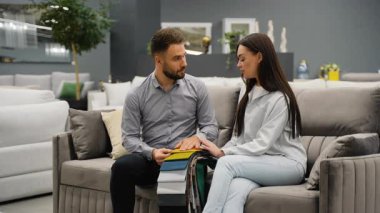 Modern bir mobilya galerisindeki yeni bir kanepenin kumaş örnekleri hakkında genç bir bayana danışan bilgili bir satıcı firma ve dostça bir tokalaşma ile başarılı bir anlaşma yaptı.